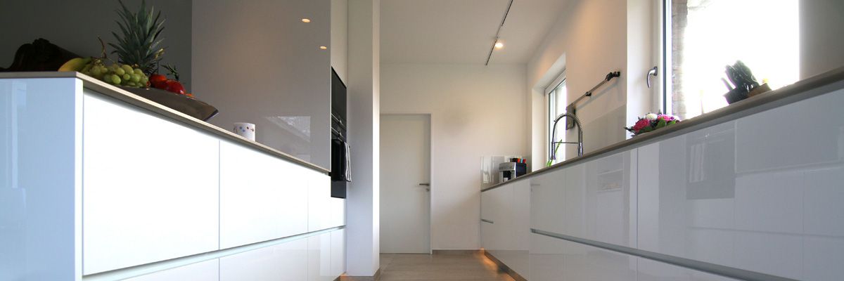 Moderne, helle Küche mit glänzenden weißen Fronten, Obstschale, Spüle und Miele Professional Geräten.